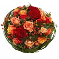 A beautiful bouquet of red and orange roses and a beautiful green trimmings....