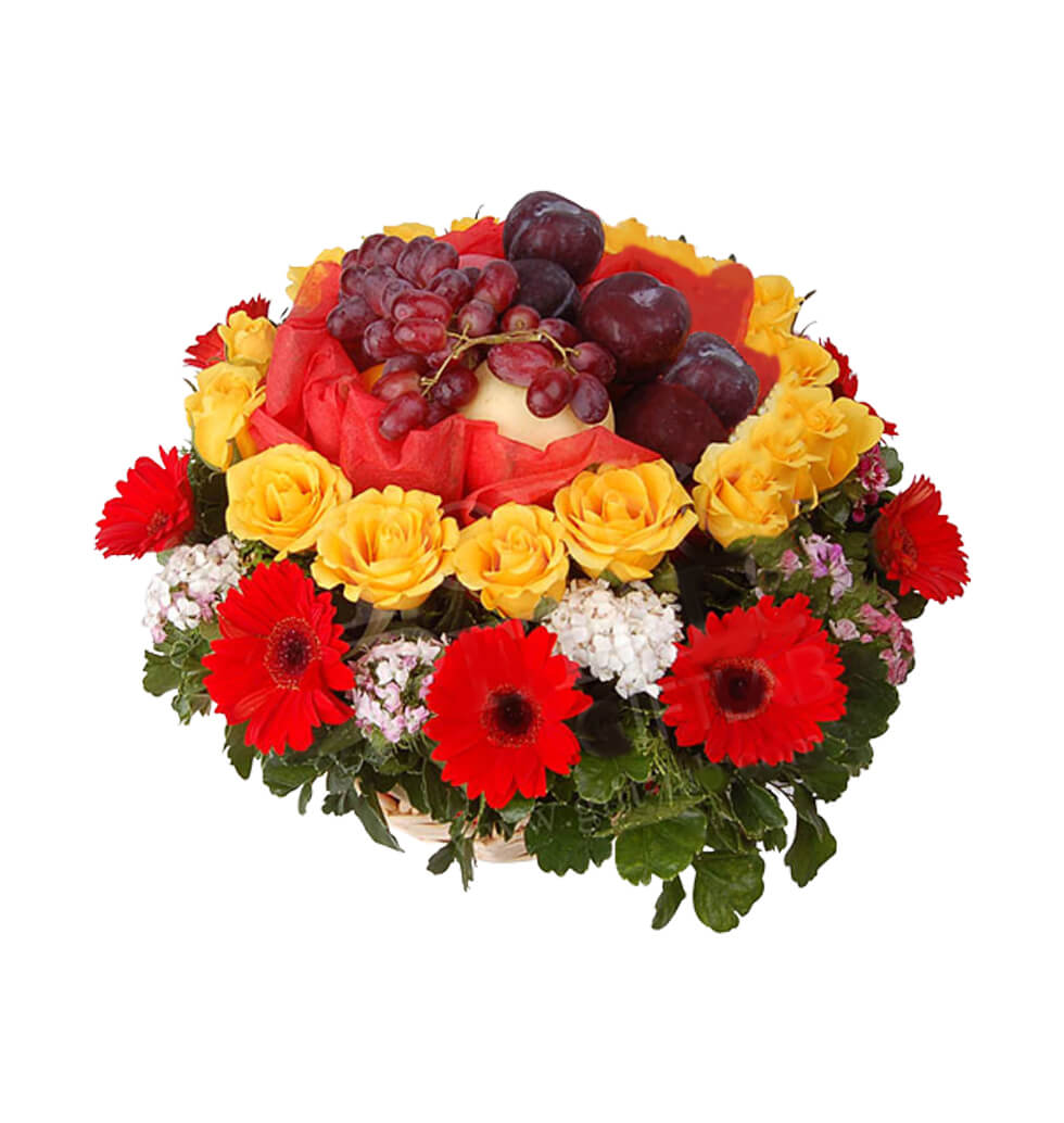 Roses and gerberas around a basket�of fruit in the...