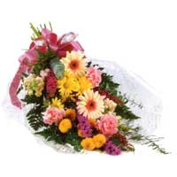 Vibrant display of seasonal flowers with liliums, roses, orange germinis, solida...