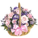 A gorgeous basket overflowing with an arrangement of seasonal flowers in bright ...