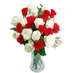 24 blended roses arranged in a clear glass vase...