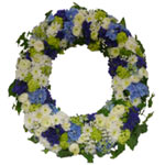 This funeral wreath, round stucked with natural with white, blue and green flowe...